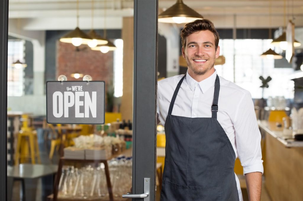 happy restaurant owner standing outside of his restaurant